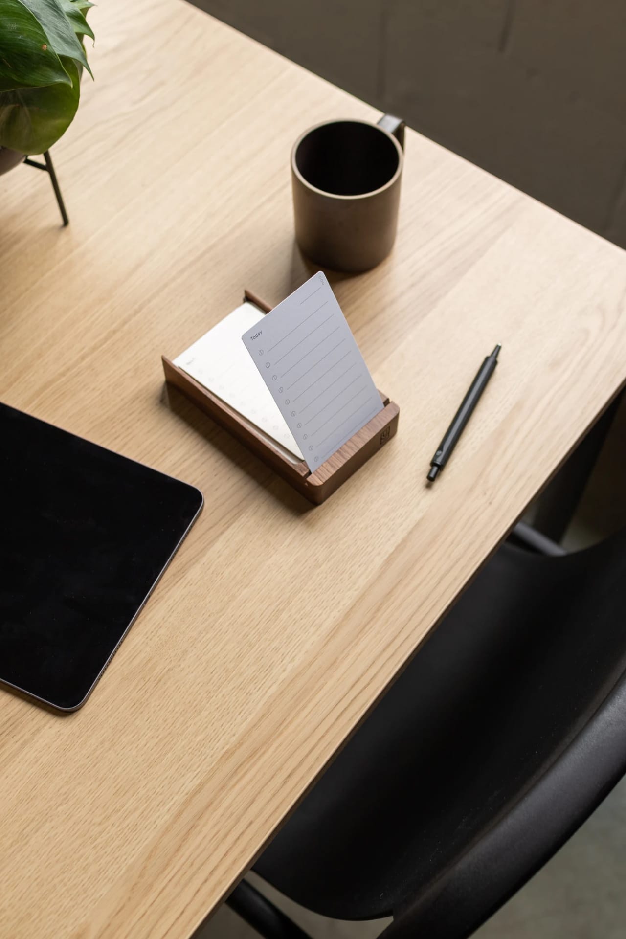 Paper card sitting upright in walnut card holder on desk.