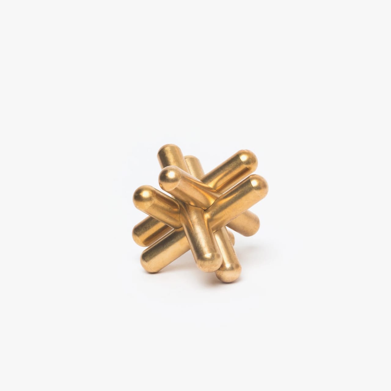 Brass puzzle in the shape of a jack with overlapping rounded posts.