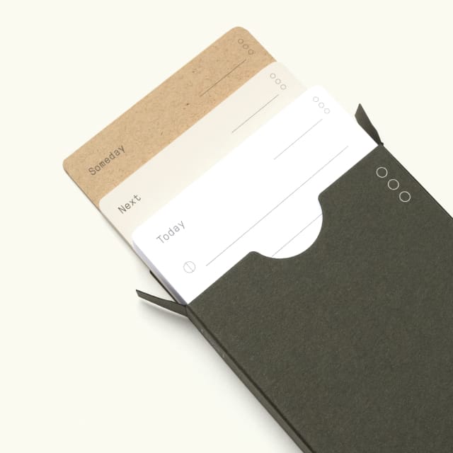 Green cardstock box containing white, beige, and brown cards.